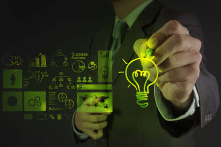 businessman hand draws lightbulb with new computer interface as solution business conceptの写真素材