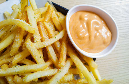 spicy french fries on tracing paper on board on wooden tableの写真素材