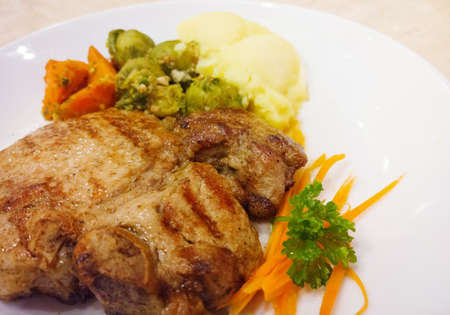 Grilled pork steaks baked potatoes and vegetable saladの写真素材