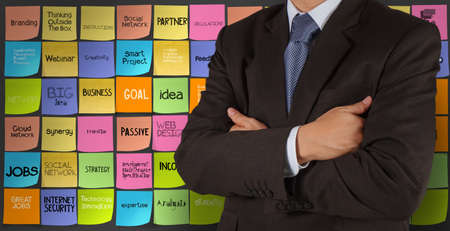 businessman and hand drawn words icons of business strategy on sticky note background as conceptの写真素材