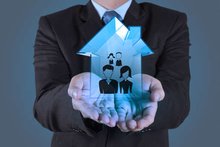 businessman hand holding 3d house wtih family icon as insurance conceptの写真素材