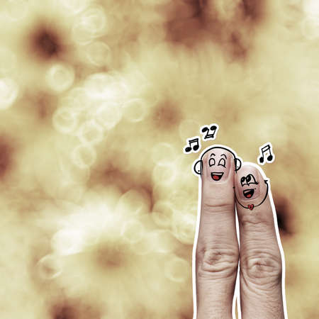 the happy finger couple in love with painted smiley and sing a song on flower nature backgroundの写真素材