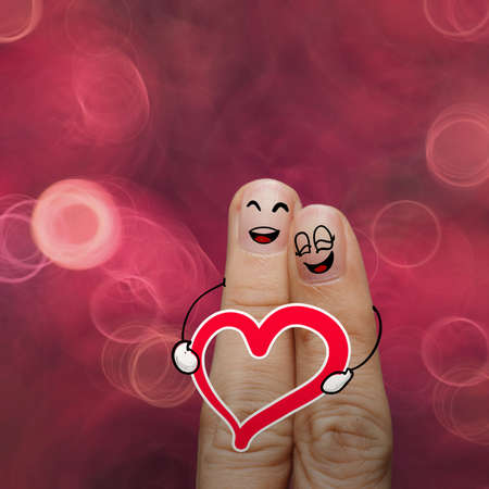 the happy finger couple in love with painted smiley and hold heart on nature backgroundの写真素材