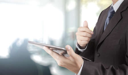 businessman hand using tablet computer and office backgroundの写真素材