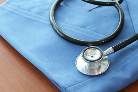 Stethoscope with blue doctor coat on wooden table and  backgroundの写真素材