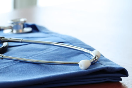 Stethoscope with blue doctor coat on wooden table with shallow DOF evenly matched and backgroundの写真素材