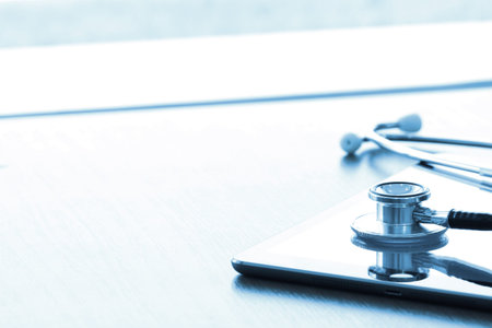 Studio macro of a stethoscope and digital tablet with shallow DOF evenly matched abstract on wood table background copy spaceの写真素材