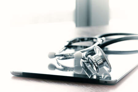 Studio macro of a stethoscope and digital tablet with shallow DOF evenly matched abstract on wood table background copy spaceの写真素材