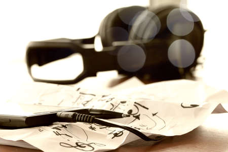 Closeup of smart phone with jack of headphone on musical notes paper with shallow DOF evenly matched on wooden deskの写真素材