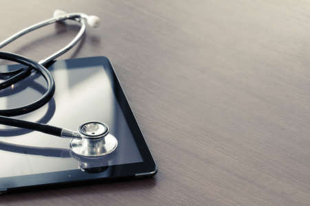 Studio macro of a stethoscope and digital tablet with shallow DOF evenly matched abstract on wood table background copy spaceの写真素材