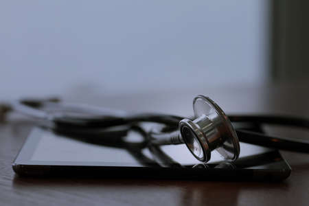 Studio macro of a stethoscope and digital tablet with shallow DOF evenly matched abstract on wood table background copy spaceの写真素材
