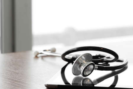 Studio macro of a stethoscope and digital tablet with shallow DOF evenly matched abstract on wood table background copy spaceの写真素材