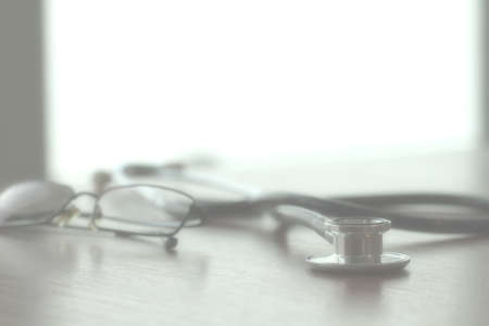 Studio macro of a stethoscope and glasses with shallow DOF evenly matched abstract on wood table background copy spaceの写真素材