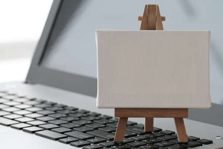 blank canvas and wooden easel on laptop computer as conceptの写真素材