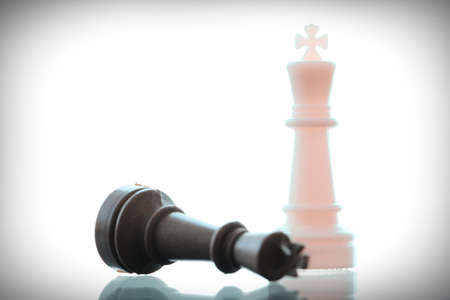close up of king chess figure surrounded by a number of fallen black chess as strategy or leadership conceptの写真素材