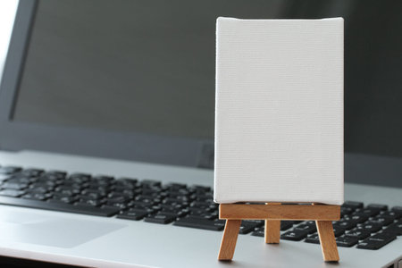 blank canvas and wooden easel on laptop computer as conceptの写真素材