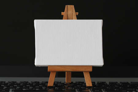 blank canvas and wooden easel on laptop computer as conceptの写真素材