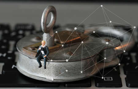 Internet security concept-miniature businessman stand on old key and padlock on laptop computer keyboardの写真素材