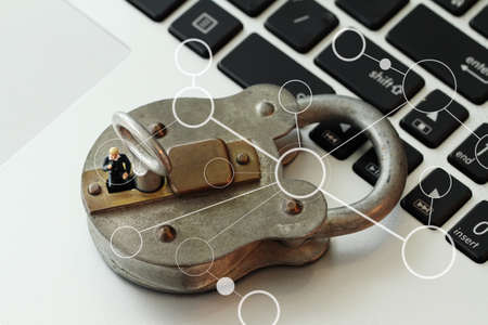Internet security concept-miniature businessman stand on old key and padlock on laptop computer keyboardの写真素材