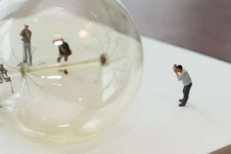 Creative idea concept - miniature photographer with vintage light bulb on open paper notebookの写真素材