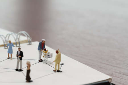 close up of miniature people with social network diagram on open notebook on wooden desk as social media coneptの写真素材