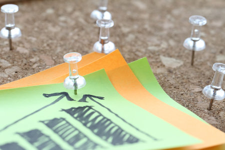 close up of pin and hand drawn business strategy graph chart on sticky note with cork board as conceptの写真素材