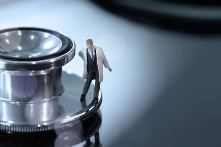 Modern medical concept- studio macro of miniature doctor with  a stethoscope and digital tablet  on wood table backgroundの写真素材