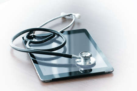 Studio macro of a stethoscope and digital tablet with shallow DOF evenly matched abstract on wood table background copy spaceの写真素材