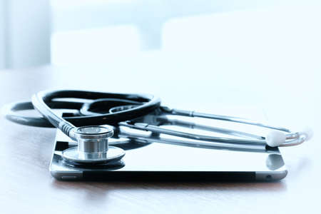 Studio macro of a stethoscope and digital tablet with shallow DOF evenly matched abstract on wood table background copy spaceの写真素材