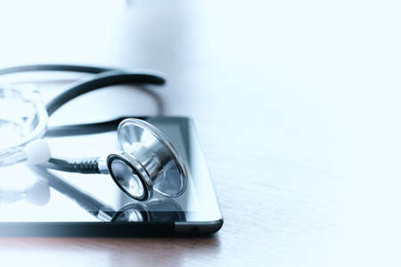 Studio macro of a stethoscope and digital tablet with shallow DOF evenly matched abstract on wood table background copy spaceの写真素材
