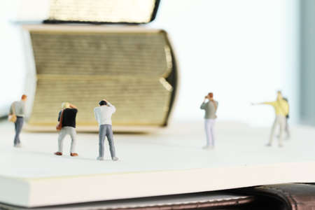 Creative idea concept - miniature photographer with vintage golden book on open paper notebookの写真素材