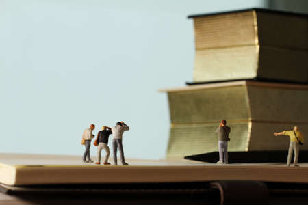 Creative idea concept - miniature photographer with vintage golden book on open paper notebookの写真素材