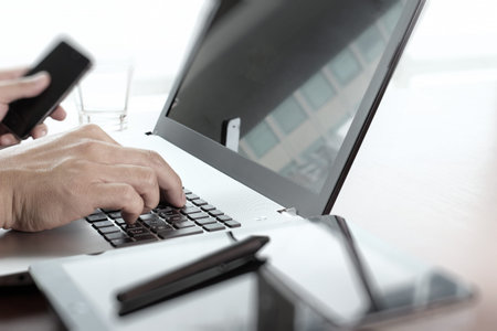 Close up of business man working on laptop computer on wooden desk as concept