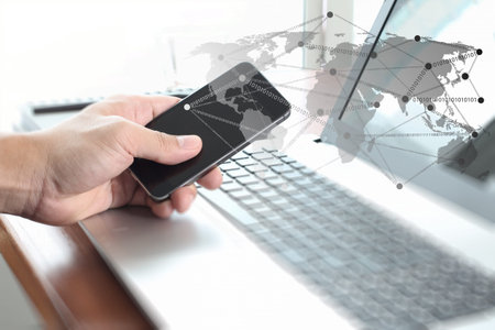 Businessman hand using laptop and mobile phone with social network diagram on wooden desk as concept
