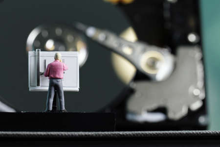 Big data concept-miniature engineer working wirh drafting table with open harddisk backgroundの写真素材