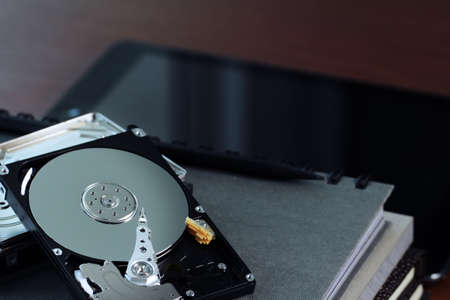 Close up of open computer hard disk drive on desk and notebookの写真素材