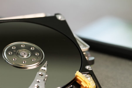 Close up of open computer hard disk drive on desk and notebook