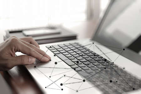 Close up of business man hand working on laptop computer with social network diagram on wooden desk as conceptの写真素材
