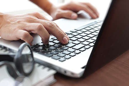 Close up of business man working on laptop computer on wooden desk as conceptの写真素材
