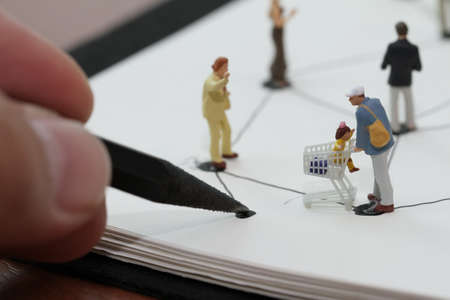 close up of miniature people with social network diagram on open notebook on wooden desk as social media conceptの写真素材
