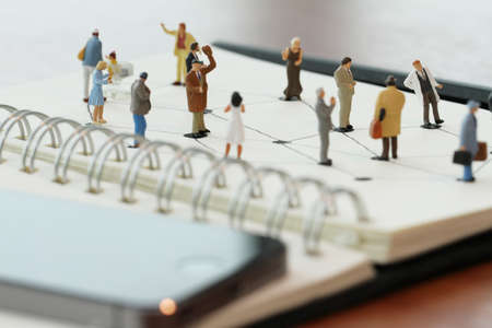 close up of miniature people with social network diagram on open notebook on wooden desk as social media conceptの写真素材