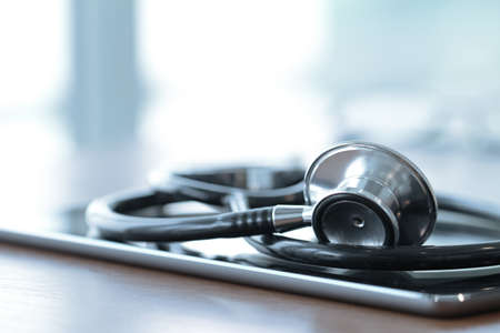 Studio macro of a stethoscope and digital tablet with shallow DOF evenly matched abstract on wood table background copy spaceの写真素材