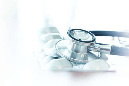 Studio macro of a stethoscope and pills with shallow DOF evenly matched abstract on wood table background copy spaceの写真素材
