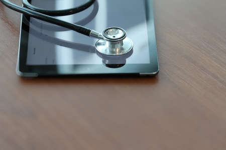 Studio macro of a stethoscope and digital tablet with shallow DOF evenly matched abstract on wood table background copy spaceの写真素材
