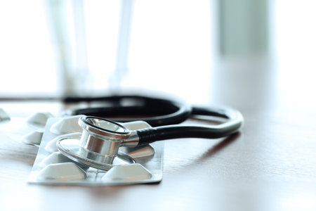 Studio macro of a stethoscope and pills with shallow DOF evenly matched abstract on wood table background copy spaceの写真素材