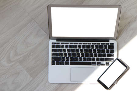 blank screen laptop computer with smart phone is on wooden desk as workplace conceptの写真素材