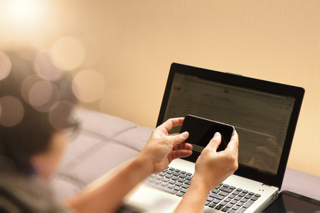 young designer working with blank screen smart phone and computer in bed as conceptの写真素材
