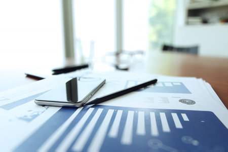 business documents on office table with smart phone and digital tablet as work space business conceptの写真素材