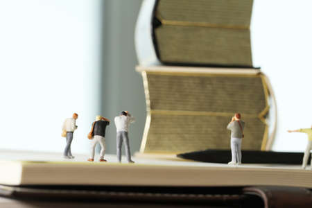 Creative idea concept - miniature photographer with vintage golden book on open paper notebookの写真素材