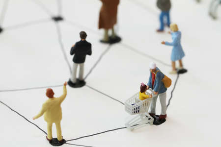 close up of miniature people with social network diagram on open notebook on wooden desk as social media conceptの写真素材